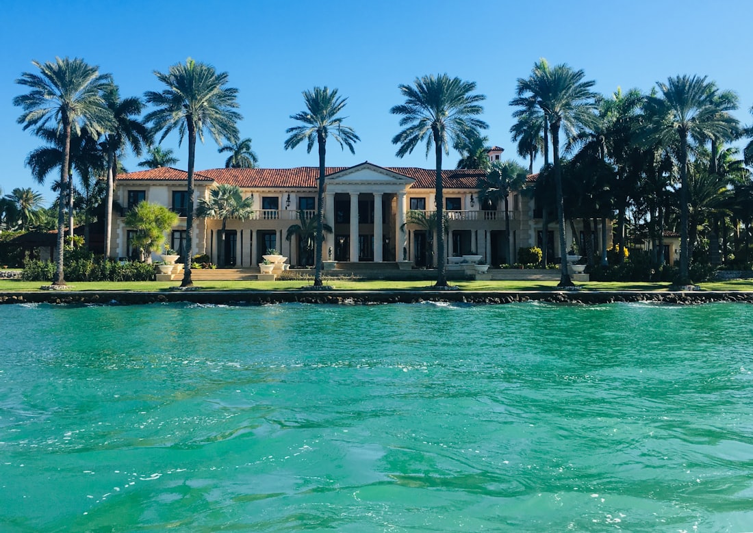Miami beachfront estate with palm-lined lawn on turquoise waterfront